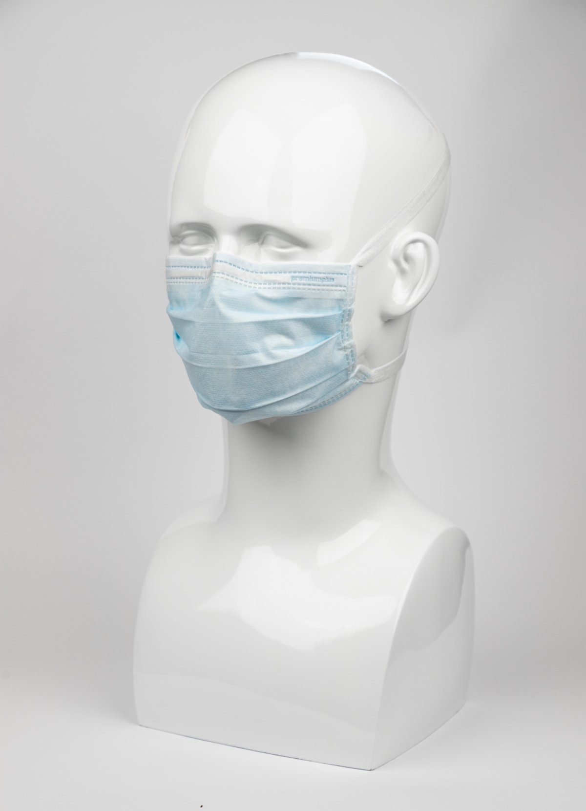 Premium Plus OP-Maske in Blau mit Kopfbändern statt Ohrschlaufen. Auf weißem Modellkopf, 3-lagig mit flexiblem Nasenbügel für sicheren und komfortablen Sitz.