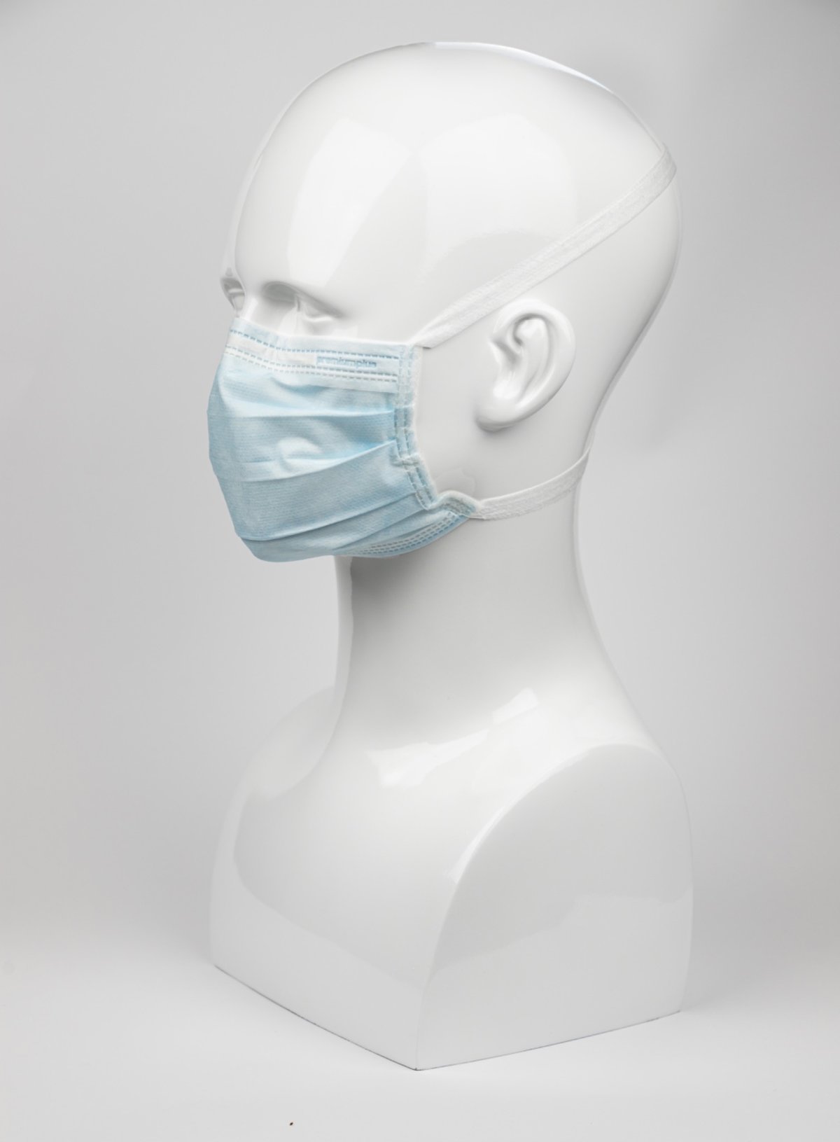 Premium Plus OP-Maske mit Kopfbändern statt Ohrschlaufen, leicht von rechts vorne fotografiert. 3-lagige Einwegmaske in Blau mit flexiblem Nasenbügel für medizinische Anwendungen.